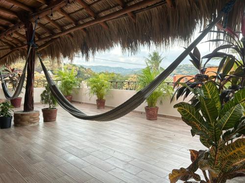 a hammock in a house with plants and a view at Posada El Mágico in Mazunte