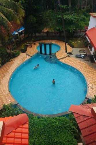 a large swimming pool with people swimming in it at The Cozy Chapter in Arpora