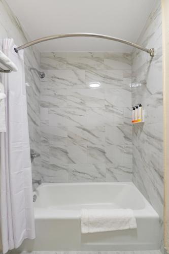 a bathroom with a white tub and a marble wall at The Prime Suites, Vallejo - Napa Valley and Six Flags Discovery Kingdom in Vallejo