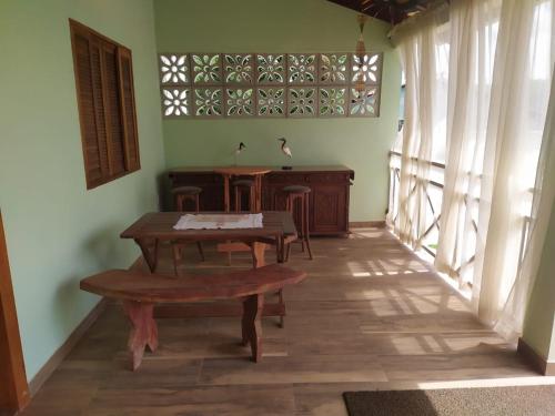 Zimmer mit einem Tisch, einer Bank und Fenstern in der Unterkunft Quintal dos Pinheiros in Pirenópolis