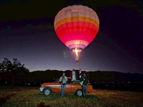 Ein Heißluftballon fliegt über einem Auto auf einem Feld in der Unterkunft Yorsong Hostel Pai in Kampong Huaibū