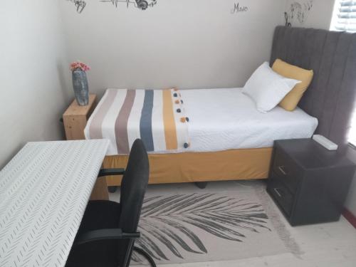 een kleine slaapkamer met een bed en een bureau bij Nested at L&MX in Centurion