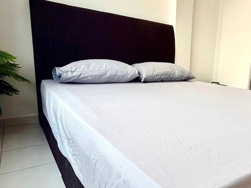 ein Bett mit einem schwarzen Kopfteil und zwei weißen Kissen in der Unterkunft Luna Bliss Taman Koop AST Lobak Budget Hotel Room in Seremban