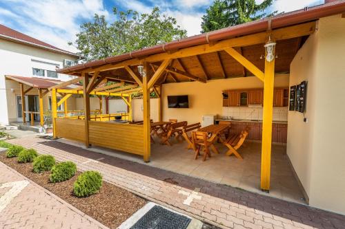 een patio met een houten terras met een tafel en stoelen bij Zama Apartman in Hajdúszoboszló