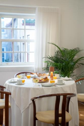 a table with a white table cloth and food on it at Hotel Toural in Guimarães