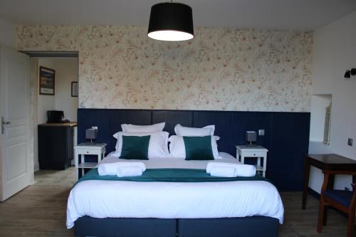 a bedroom with a large bed with green and white pillows at Domaine Des Piéris - Chambres d'Hôtes in Grandcamp-Maisy