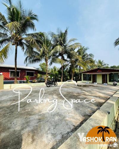 un aparcamiento con palmeras frente a un edificio en Yashokiran Farmstay, en Borlai