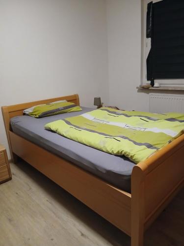 Doppelbett für Zwei في دينسلاكن: سرير بإطار خشبي وعليه بطانية صفراء