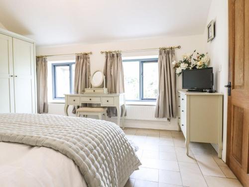 a bedroom with a bed and a desk and a television at The Talkhouse Cottage in Caersws