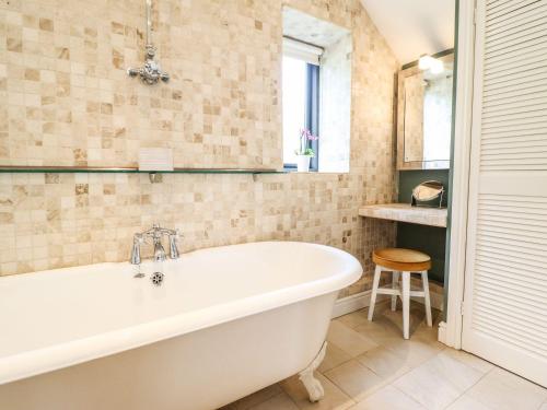 a bath tub in a bathroom with a window and a stool at The Talkhouse Cottage in Caersws