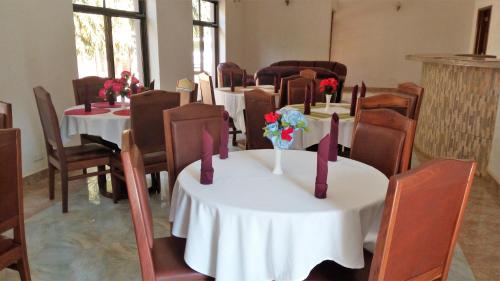 a room with tables and chairs with flowers on them at Sangana Lodge in Moshi