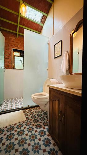 a bathroom with a toilet and a sink and a mirror at Green Roots Farm Stay, Shahapur in Shāhāpur