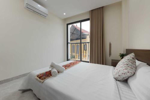 a bedroom with a large white bed with a window at Collection O West Lake Apartment in Hanoi
