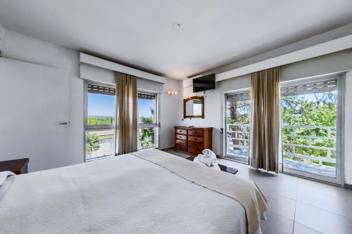 a bedroom with a large white bed and windows at Gran Hotel Las Lajas in Villa Carlos Paz