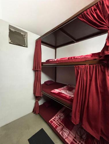 two bunk beds in a room with red curtains at Shivanand Aashray - Near Sangam in Prayagraj