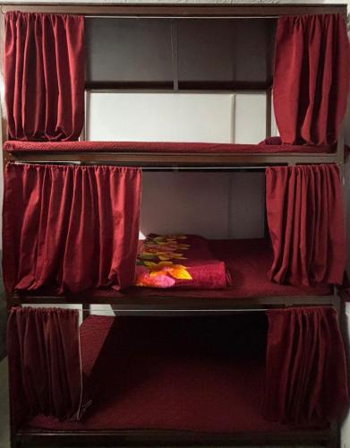 an empty bunk bed with red curtains in a room at Shivanand Aashray - Near Sangam in Prayagraj