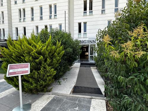 a sign in front of a building with bushes at Big Inn Luxury Hotel in Biga
