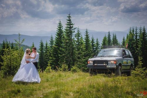 a bride and groom standing in a field next to a car at Arkan in Mykulychyn