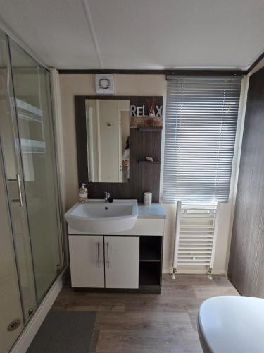 ein Badezimmer mit einem weißen Waschbecken und einer Dusche in der Unterkunft Rody's Cosy Corner in Crowle