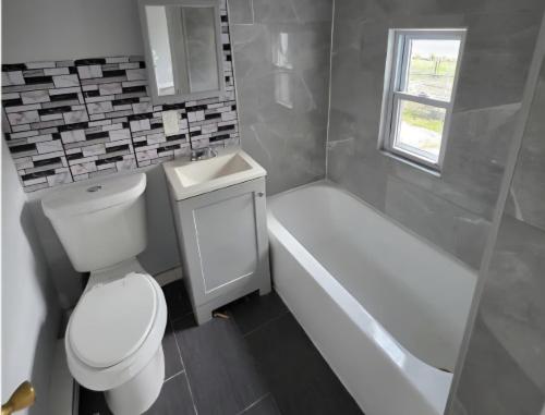 a bathroom with a toilet and a sink and a tub at Bright Private Room Shared Bathroom in Elizabeth