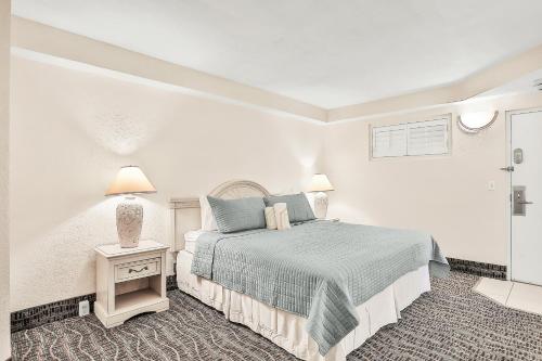a white bedroom with a bed and a side table at Daytona Beach Resort 533- Oceanfront Oasis in Daytona Beach