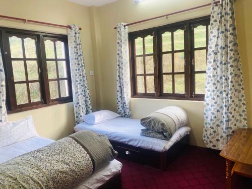 2 camas en una habitación con ventanas y sofá en Bhaktapur Yog Homestay, en Bhaktapur
