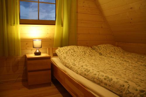 um quarto com uma cama com um candeeiro numa mesa de cabeceira em Chatka pod Tatrami em Kościelisko