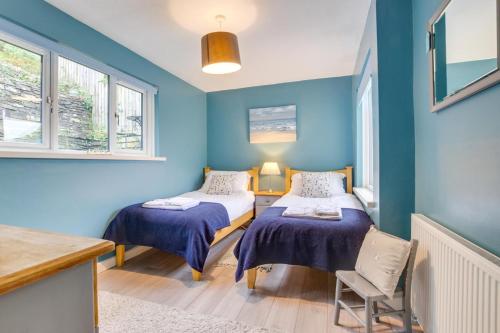 two beds in a room with blue walls and windows at 2 Bed in Looe oc-l10082 in Looe