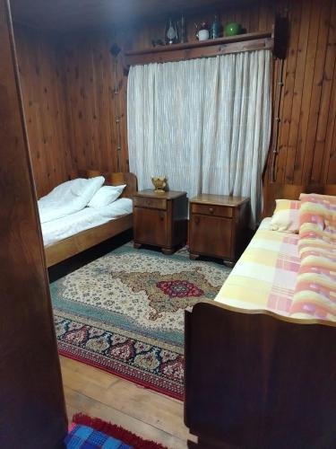 a bedroom with two beds and a window and a rug at Brvnara Zlatni mir in Vodice