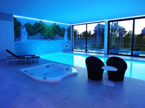 a large swimming pool with a tub and chairs at B&B Vita Roka met extra Luxe Privé Wellness in Ursel