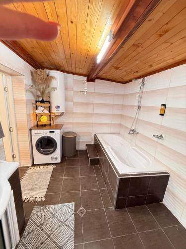 a bathroom with a tub and a washing machine at Вила Лонгоз in Dŭbravino