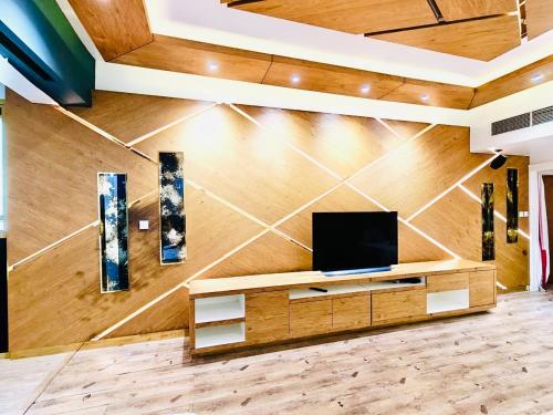 a living room with a tv on a wooden wall at La Vista Home Stay with Parking in Ajman