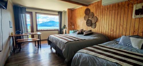ein Schlafzimmer mit zwei Betten und einem großen Fenster in der Unterkunft Tranquilo Austral in Puerto Tranquilo