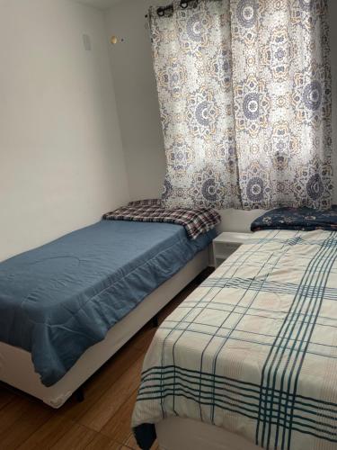 a bedroom with two twin beds and a curtain at Decoradinho RJ in Rio de Janeiro