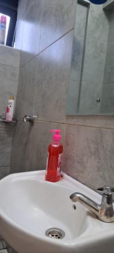 a red bottle of soap sitting on a bathroom sink at The cozy nook - Thindigua in Kiambu