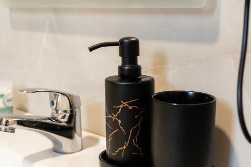 a black soap dispenser on a sink next to a cup at Central Gem Tirana in Tirana