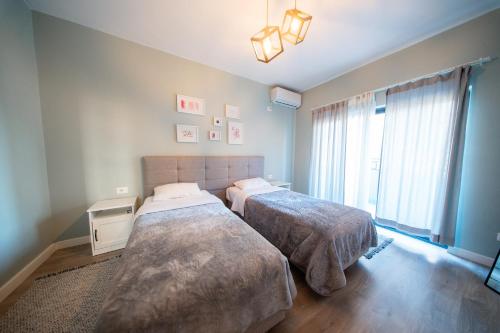 a bedroom with two beds and a large window at Central Gem Tirana in Tirana