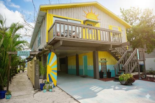 a house with a balcony and a surfboard at Anna Maria Island Beach Shack Walk to Beach & Bay in Bradenton Beach
