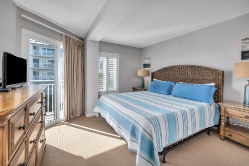 a bedroom with a bed with blue pillows and a television at Beach Club #211 in East End
