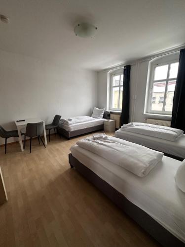 2-Zi-Wohnung und Parkplatz für Geschäftsreisende في رودرسدورف: غرفة نوم بثلاث اسرة وطاولة وكراسي