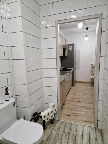 Un baño con inodoro y una cocina. en SAWAGO przytulne mieszkanie u Gosi Lekowo Ciechanów, 