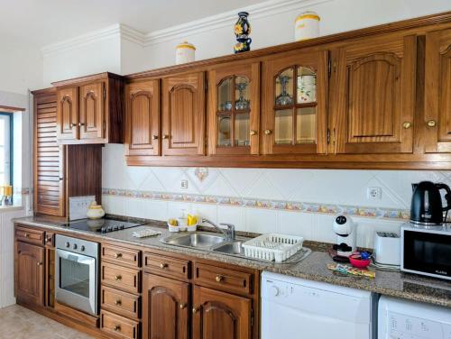 a kitchen with wooden cabinets and a sink at Onda Atlântica - Atlantic Wave Peniche in Peniche