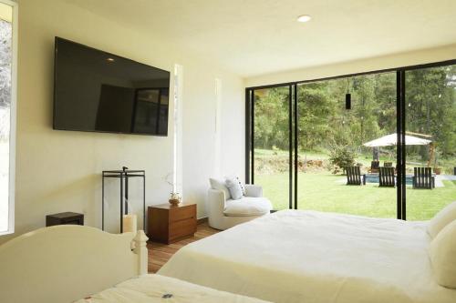 Un dormitorio con dos camas y una gran ventana. en La Malenita casa en Amanalco, en Amanalco de Becerra