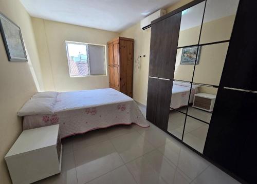a small bedroom with a bed and a mirror at Res Mariscal em Bombinhas in Canto Grande