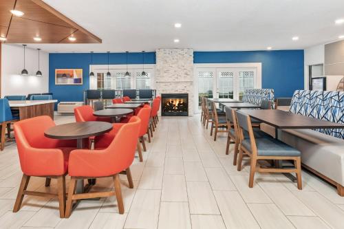 a restaurant with tables and chairs and a fireplace at Holiday Inn Express Hotel & Suites Bloomington-Normal University Area by IHG in Bloomington