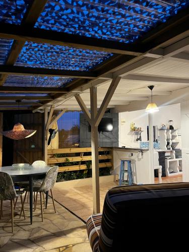 een patio met een tafel en stoelen en een keuken bij Caraiba - Maisons de Vacance avec Piscine et Toit Terrasse in Sainte-Anne