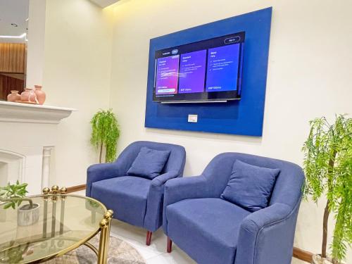 een woonkamer met twee blauwe stoelen en een televisie bij Atlantis Hotel - Boutique Stay in Downtown Cairo in Caïro