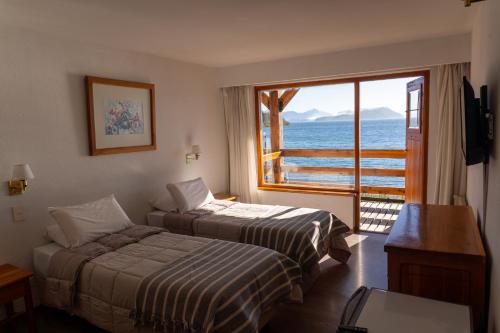 a hotel room with two beds and a large window at Apart Del Lago in San Carlos de Bariloche