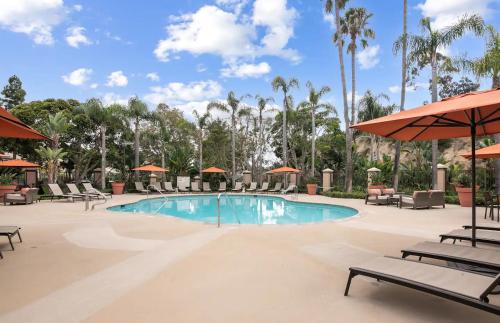 a pool with chairs and umbrellas at a resort at Stylish 1BR with KING Bed, Pool, Jacuzzi & Gym, Free Parking, Near UCSD in San Diego