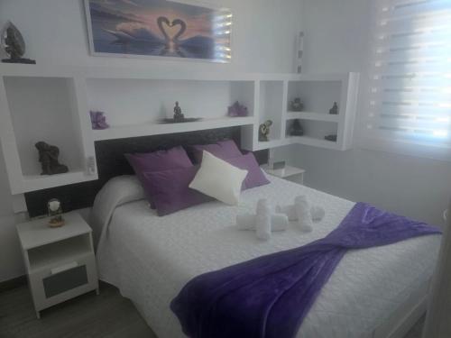 a bedroom with a bed with purple and white pillows at Medano Time in El Médano